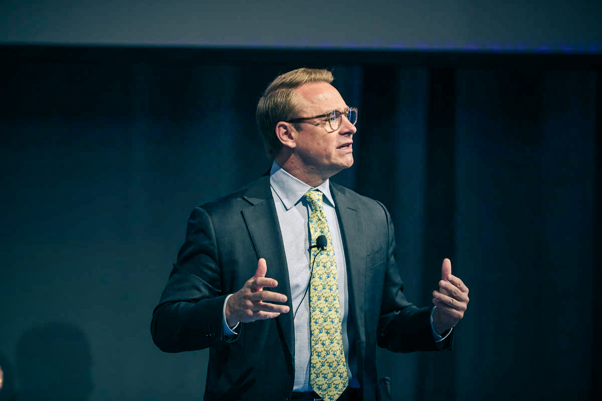 Man in a suit and tie with glasses speaking.