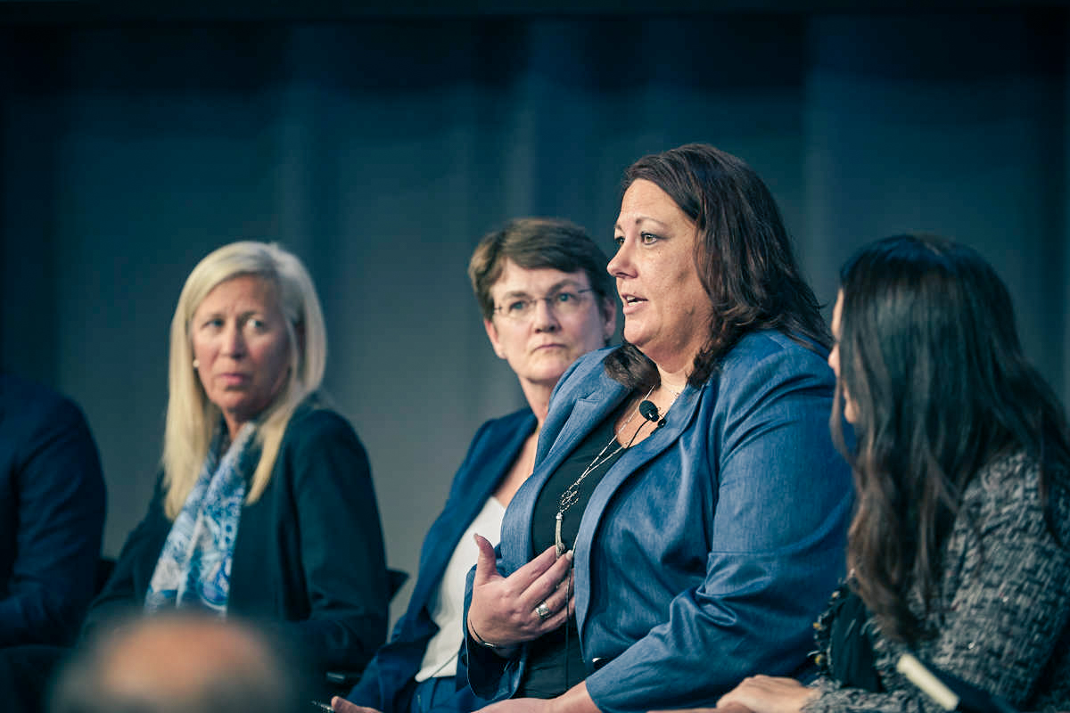 4 women sit together and one is speaking as the others look on.